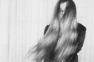 Schwarz-weiß-Foto von Lena Willikens, die durch die langen sich bewegenden Haare vor ihrem Gesicht kaum erkennbar ist.
