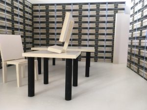 Auf dem Bild ist ein Modell von einem hellen Archivraum mit vielen Regalen, zwei Tischen und einem Stuhl. Auf einem der Tische steht ein Monitor.